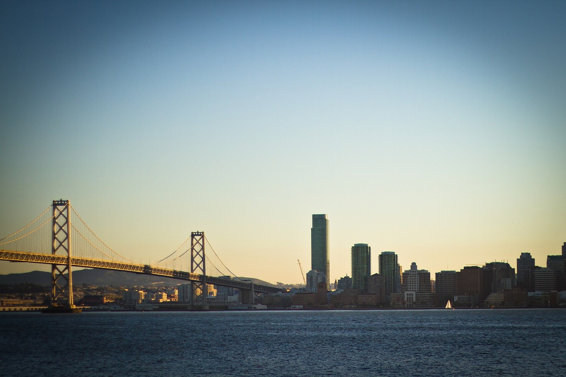 The Bay Bridge and the towers of downtown San Francisco across the water at sunset