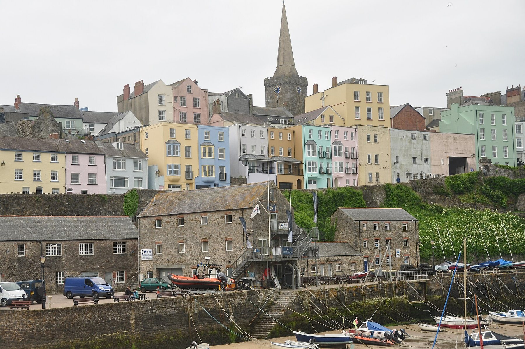 Tall painted houses above a harbour wall in a Welsh seaside town, seen from the harbour