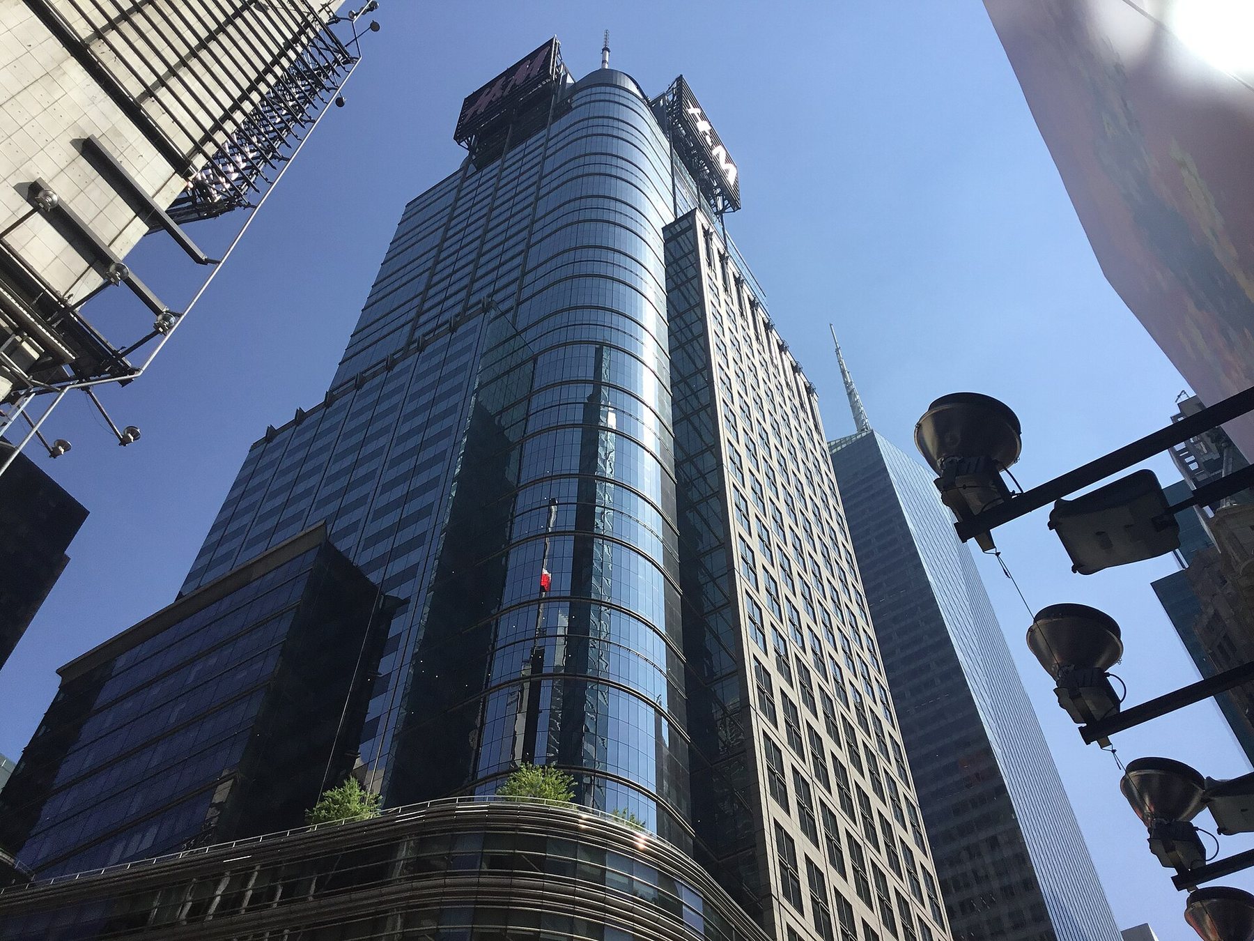 A tall glass office tower in Times Square seen from the street in daylight