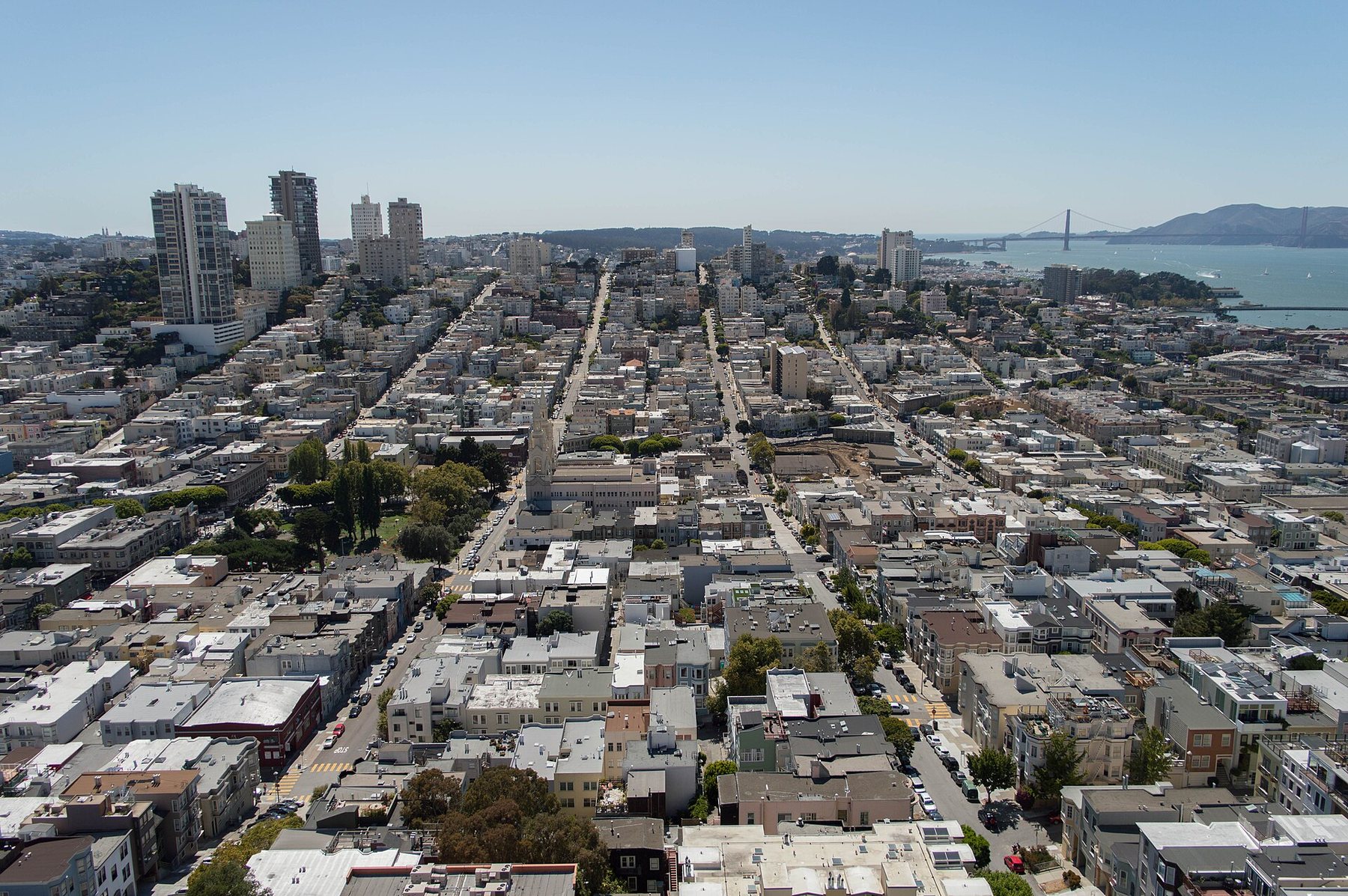 San Francisco seen from Coit Tower: streets of low apartment buildings and houses climbing a hill, with the bay beyond