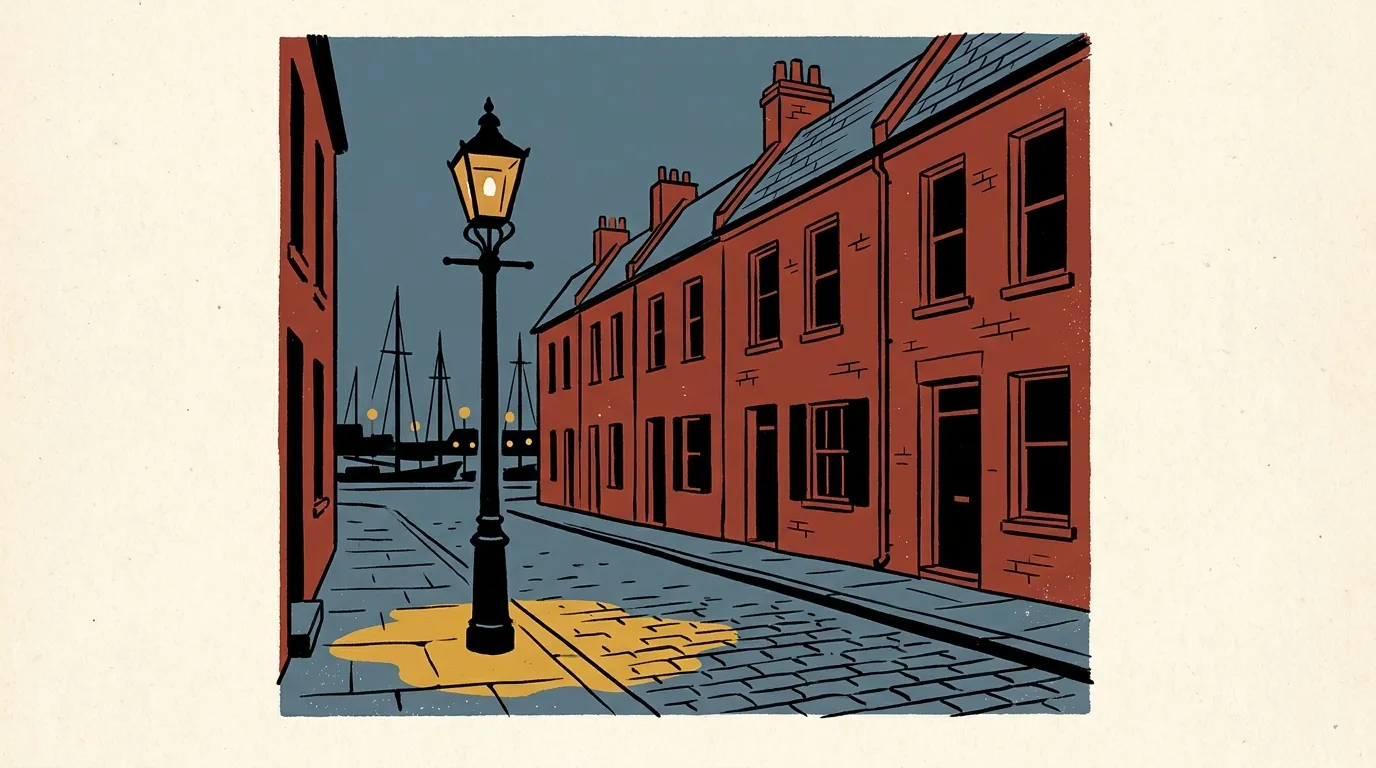 A historic cobblestone street with brick townhouses at dusk, featuring a single lamppost and sailboat masts in the background.