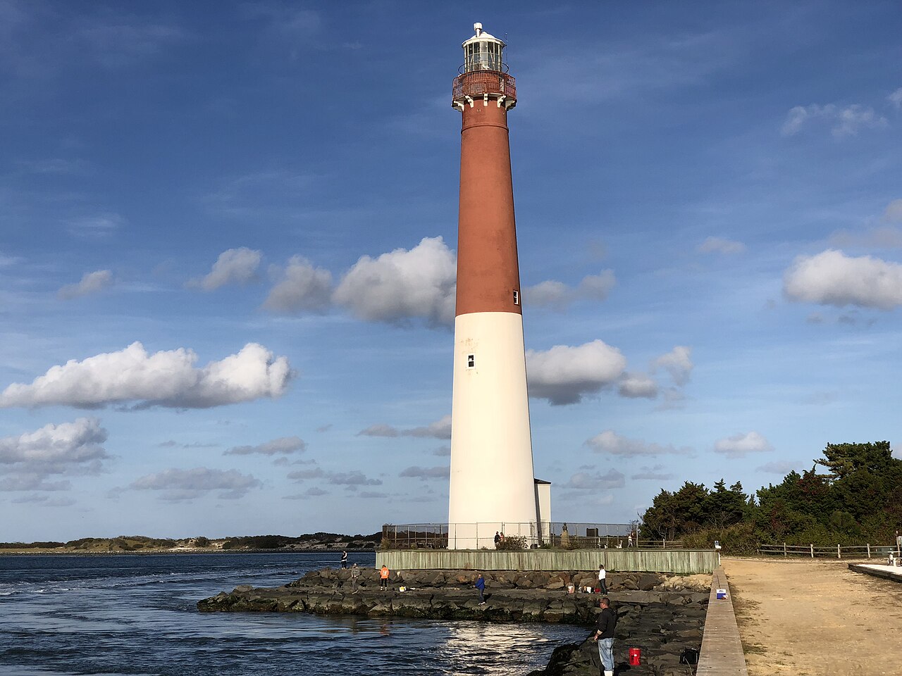 A tall lighthouse tower stands in a coastal park.