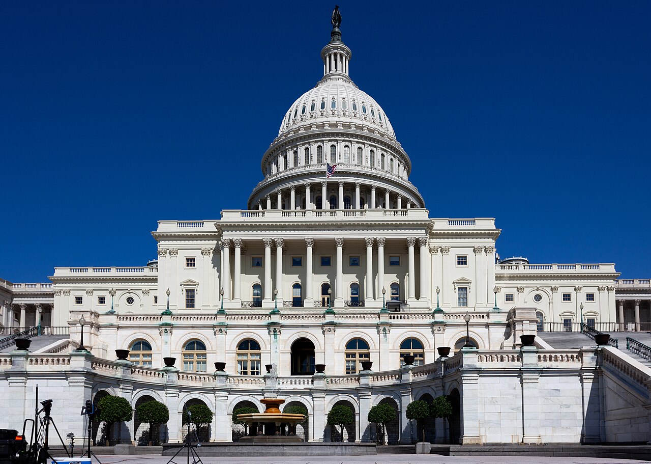 A white domed building with rows of columns and wide terraces, set against a deep blue sky.