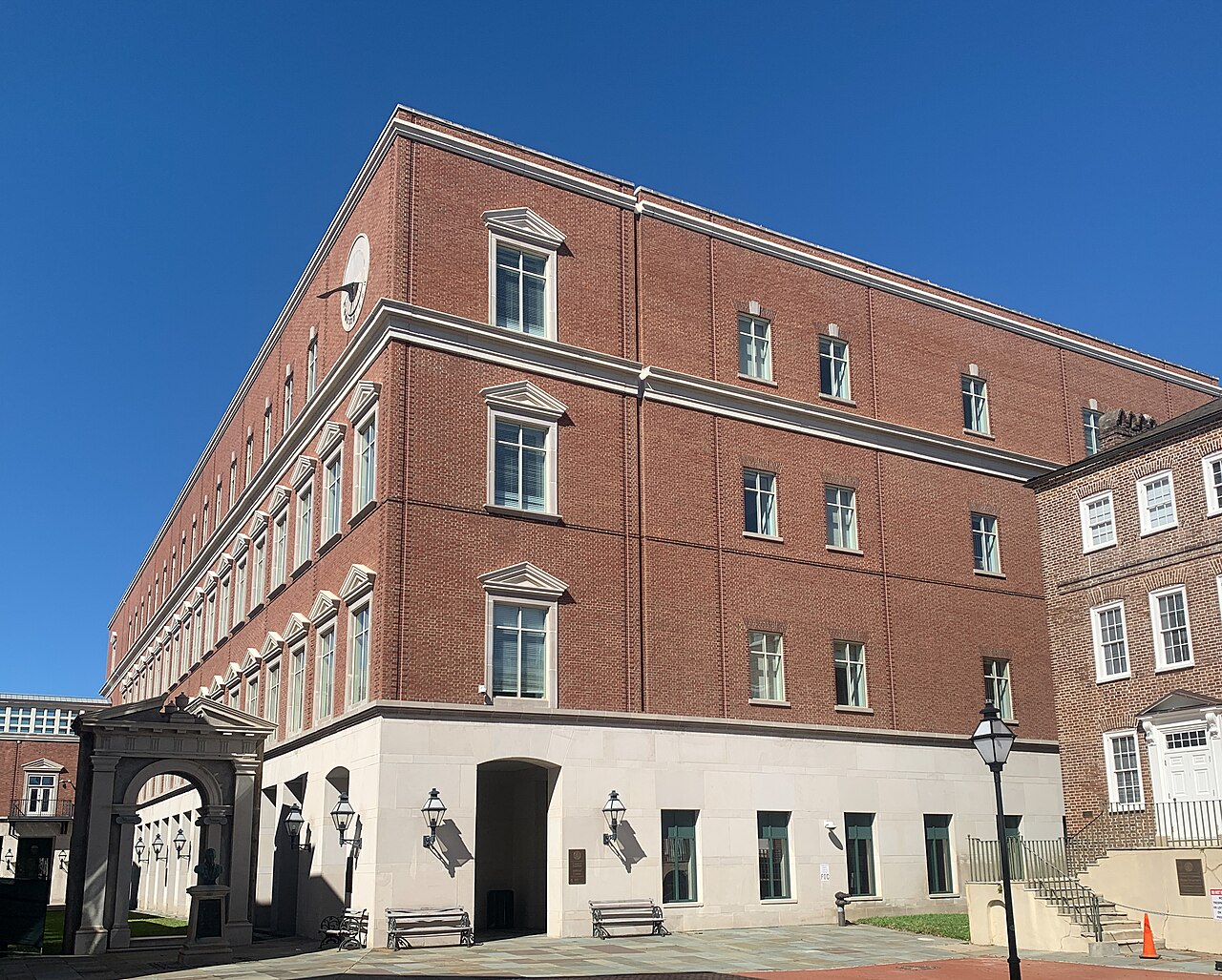 A four-storey red brick building with white-trimmed windows and a pale stone ground floor, seen from a street corner.