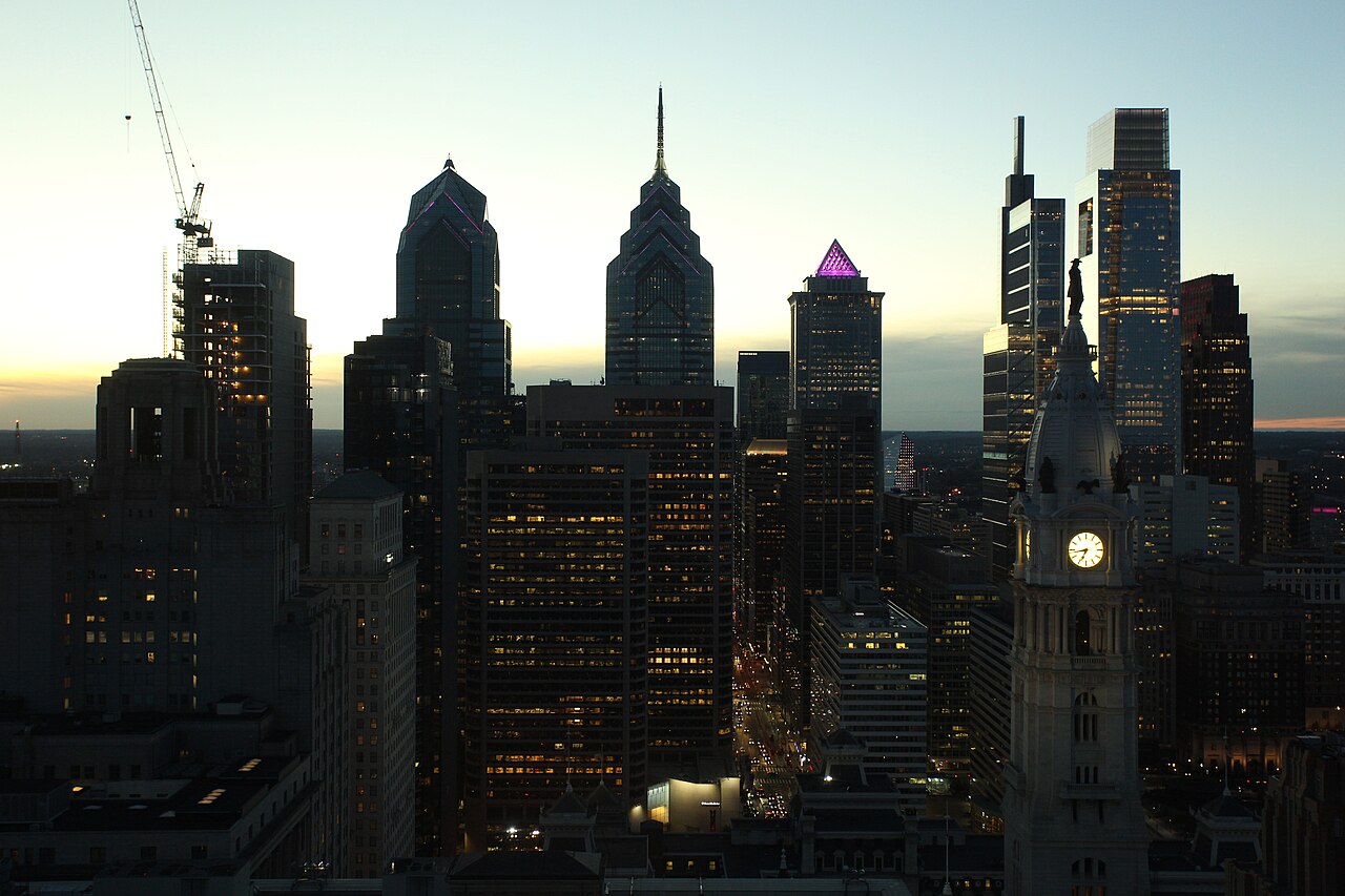 Dark high-rise towers in silhouette against a fading sky, with a lit clock tower on the right.