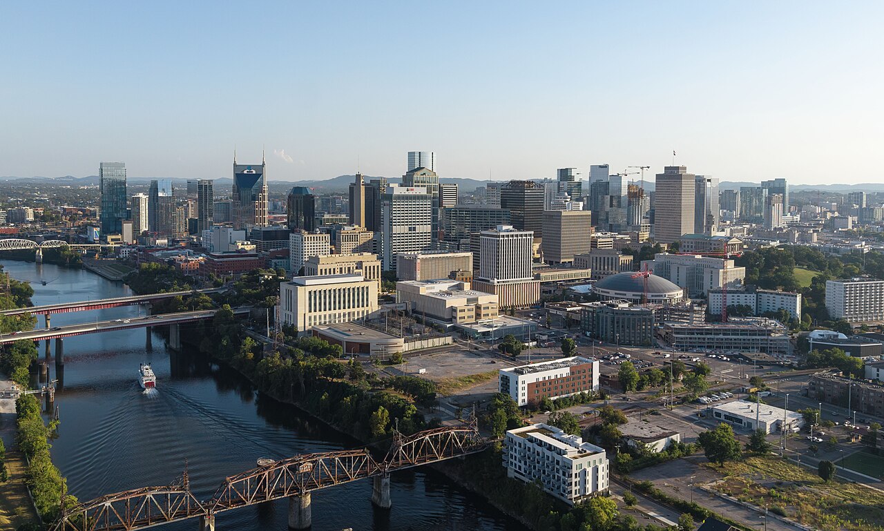 An aerial view of a downtown cluster of towers beside a curving river crossed by several bridges.