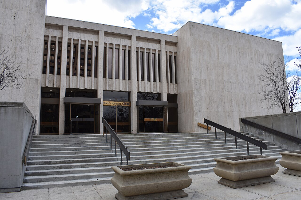 A pale stone modernist building with tall narrow window bays and broad steps leading up to its entrance.