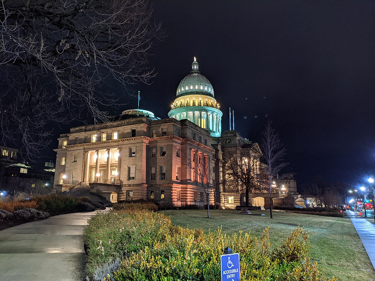 A domed sandstone capitol building floodlit at night, with a curving path and lawn in front.