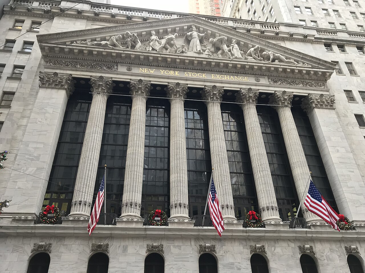 Six fluted stone columns below a carved pediment, with American flags flying along the base.