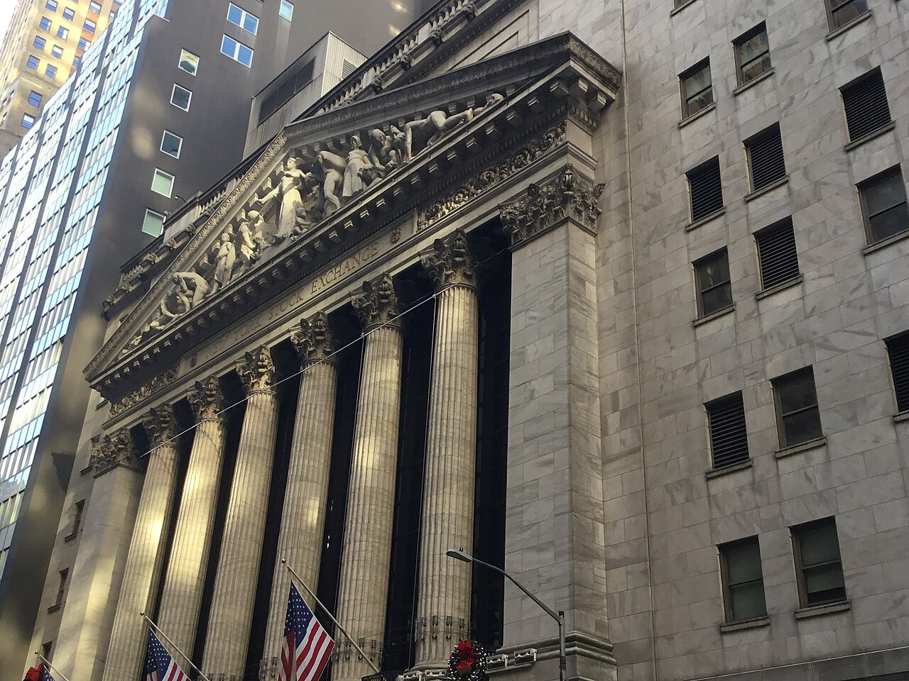 A columned stone building with a sculpted pediment seen at an angle from the street below.