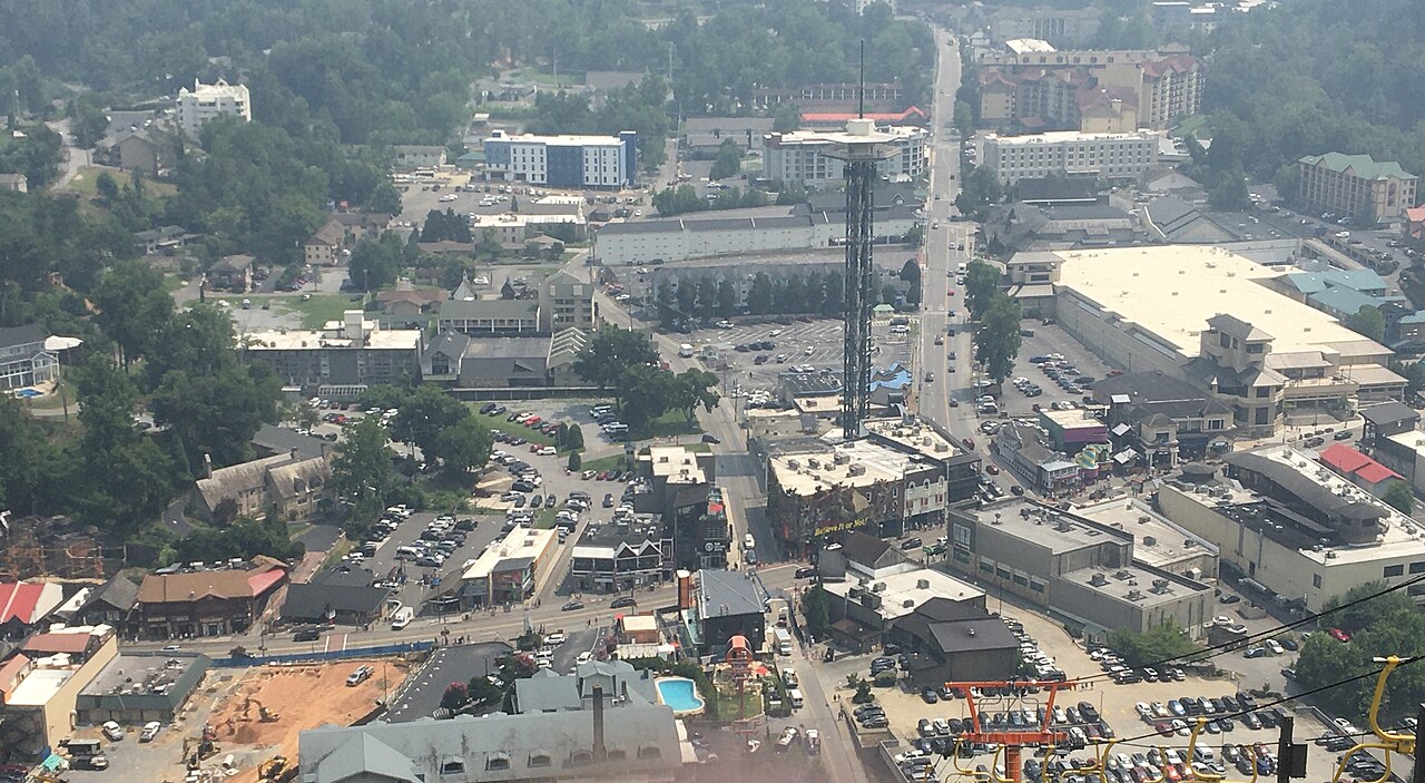 A small town packed with hotels, car parks and a tall observation tower along a main road, surrounded by wooded hills.