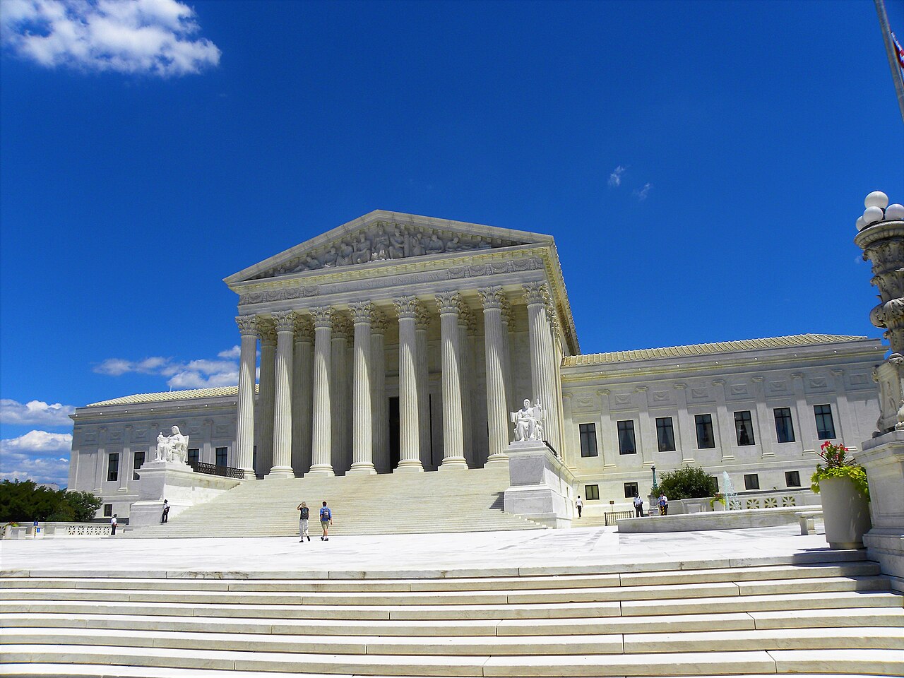 A white marble building with a row of tall columns and a wide flight of steps under a deep blue sky.