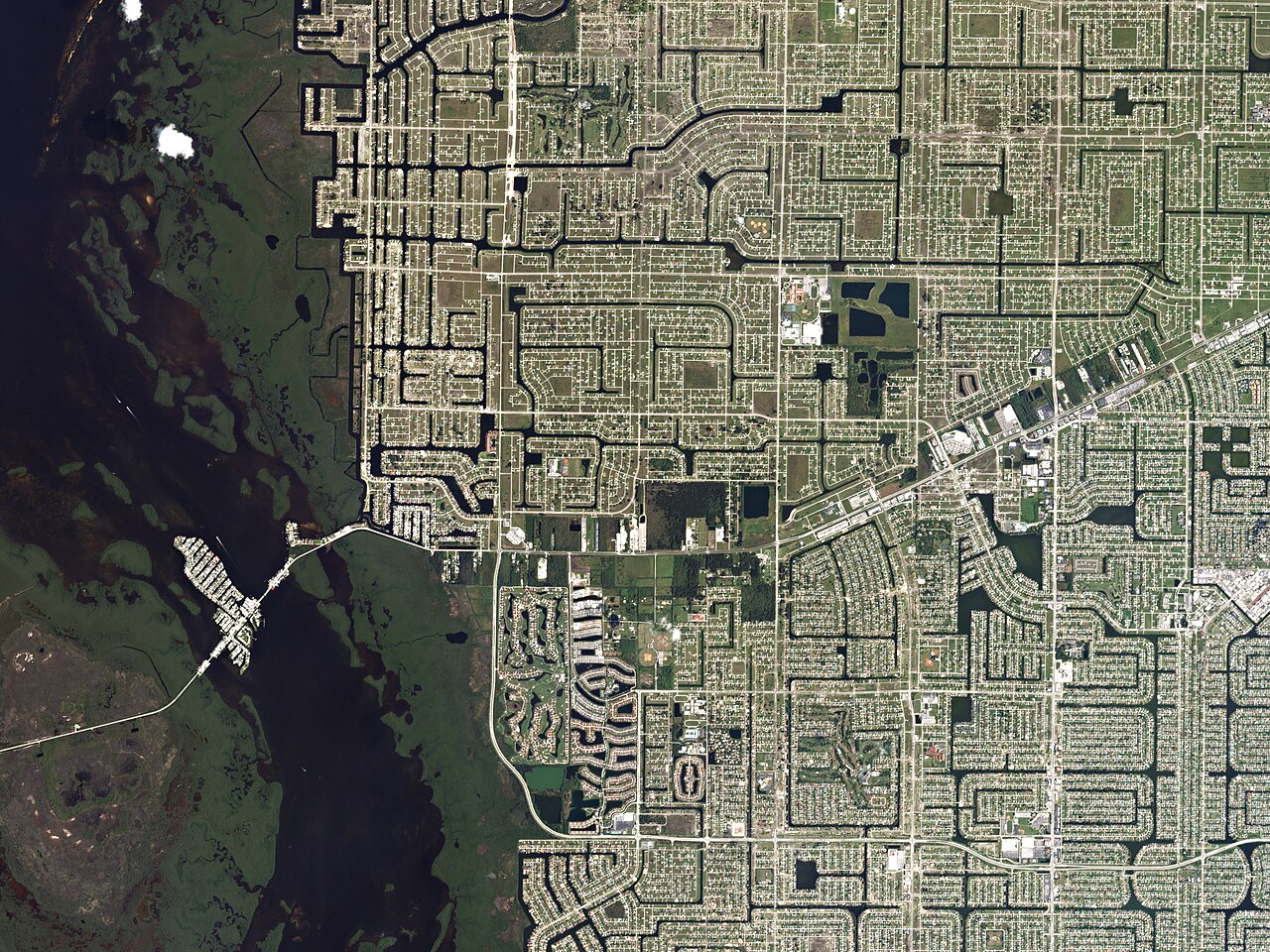 A dense grid of streets and narrow canals beside a dark river, seen from directly overhead.